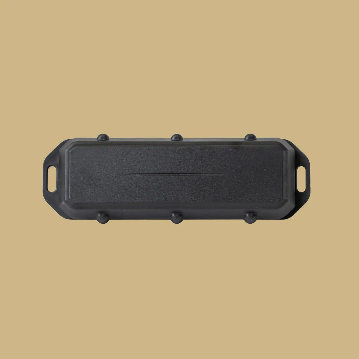 Boîtier GPS noir, plat et allongé, aux extrémités percées pour la fixation, sur fond beige.